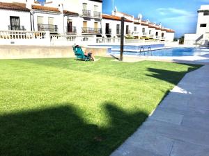una persona sentada en una silla de césped junto a una piscina en Apartamento El Primer Sol, en Nerja