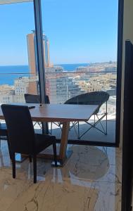 - une table et des chaises dans une chambre avec vue dans l'établissement St Julian's Mercury Tower 13th floor Luxury Apt 1302 in Tallest Tower in Malta, à San Ġiljan