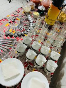 a table topped with white plates and bowls and glasses at Hotel Brasília Park in Novo Gama