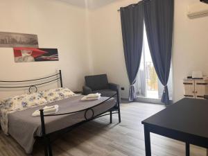 una camera con letto, sedia e tavolo di Ortigia Home a Siracusa