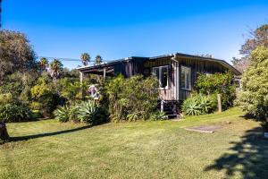 a black house with a yard in front of it at Drop Anchor at Enclosure Bay Beach by Waiheke Unlimited in Oneroa