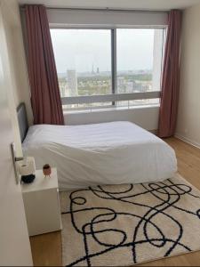 a bedroom with a bed and a large window at Logement cosy-chic Paris La Défense in Puteaux