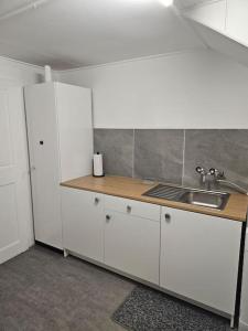 eine Küche mit weißen Schränken und einem Waschbecken in der Unterkunft L'appart - Couvet in Couvet