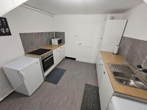 eine kleine Küche mit weißen Schränken und einem Waschbecken in der Unterkunft L'appart - Couvet in Couvet