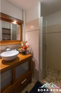 ein Bad mit einem Waschbecken und einer Dusche in der Unterkunft Black Pearl Lodge in Bora Bora