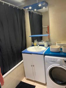 uma casa de banho com um lavatório e uma máquina de lavar roupa em Logement cosy-chic Paris La Défense em Puteaux
