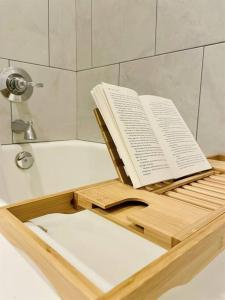 an open book on a wooden tray in a bath tub at Spacious Waterfront Cottage + 2.5 Acres on the Bay in Lafayette