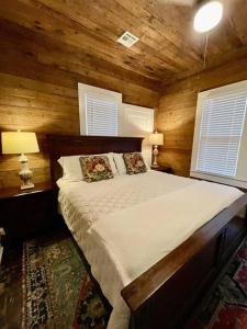 a bedroom with a bed with wooden walls and windows at Spacious Waterfront Cottage + 2.5 Acres on the Bay in Lafayette