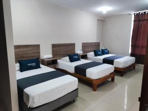 ピウラにあるConde Hotel Mirafloresの青い枕が付くベッド3台が備わる部屋