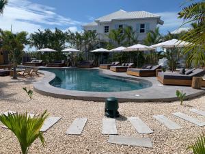 una piscina con tumbonas y sombrillas en un complejo en Casa Serena + The Pool Club @ Mahogany Bay en San Pedro