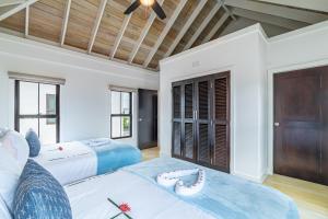 a bedroom with two beds and a large window at Casa Serena + The Pool Club @ Mahogany Bay in San Pedro