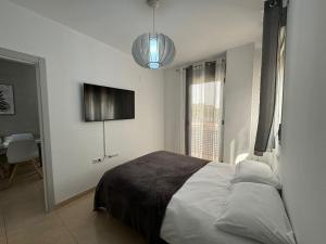 a bedroom with a bed and a television in it at Experience Valencia Bnb - Mare Nostrum Apartment Beach Puerto Sagunto in Puerto de Sagunto