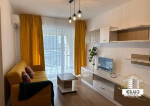 uma sala de estar com um sofá amarelo e uma televisão em Cluj Viva Aparthotel em Cluj-Napoca
