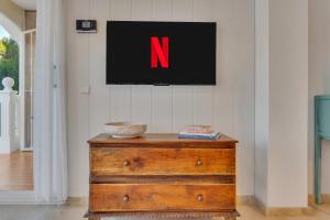 a tv on a wall above a wooden dresser with the letter n at Casita Bonita - with private garden near beach in Jávea in Jávea