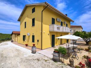 Tollo的住宿－la Casa del Vino - Il Cerchio，黄色的房子,配有桌子和雨伞
