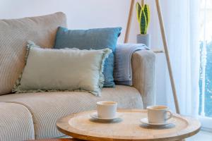 two coffee cups on a wooden table in front of a couch at Casita Bonita - with private garden near beach in Jávea in Jávea