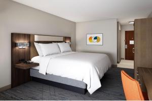 1 dormitorio con 1 cama blanca grande y sillas naranjas en Holiday Inn Express Suites Little Rock West, an IHG Hotel, en Little Rock