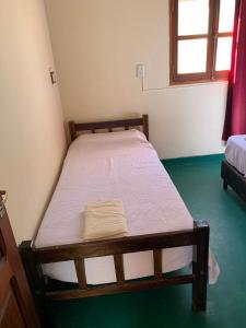 a wooden bed in a room with green floors at Cabaña Cortaderas Cachi Salta in Cachí