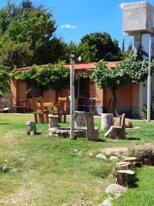 a house with a yard with wooden benches and a building at Cabaña Cortaderas MI Campito Cachi Salta in Cachí