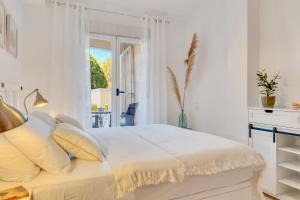 a white bedroom with a bed and a window at Casita Bonita - with private garden near beach in Jávea in Jávea