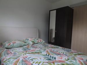 a bed with a colorful comforter and a mirror at Charmante maison avec jardin à Guidel, proche nature in Guidel