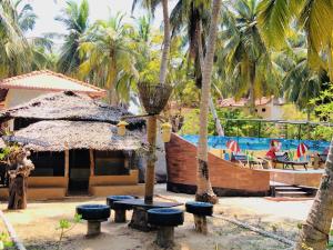 a resort with a boat and a table and palm trees at Wind Blend Kite Resort in Kalpitiya