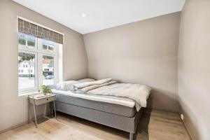 a bed in a room with a window at Romslig 3-soveroms toppleilighet midt i sentrum in Egersund