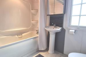 ein Badezimmer mit einem Waschbecken, einer Badewanne und einem WC in der Unterkunft Sunset View in Gillingham