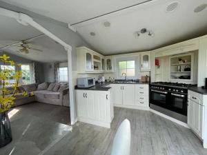 una cocina con armarios blancos y un sofá. en Sunset View, en Gillingham