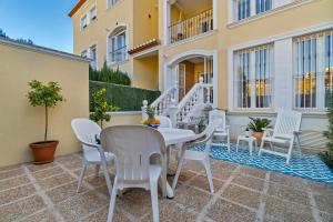 a patio with a white table and white chairs at Casita Bonita - with private garden near beach in Jávea in Jávea