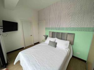a bedroom with a white bed and a flat screen tv at Sefje - Relax in the City in Guatemala