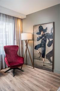 Radisson Blu Hotel, Hamburg Airport في هامبورغ: غرفة معيشة فيها كرسي احمر ولوحة