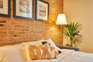 een slaapkamer met een bakstenen muur en een bed met kussens bij Catalan Comfort near Sagrada Familia by MyRentalHost in Barcelona