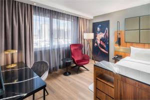 a hotel room with a bed and a red chair at Radisson Blu Hotel, Hamburg Airport in Hamburg