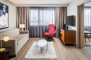 a living room with a couch and a red chair at Radisson Blu Hotel, Hamburg Airport in Hamburg