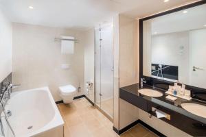 a bathroom with two sinks and a tub and a toilet at Radisson Blu Hotel, Hamburg Airport in Hamburg