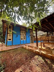 una casa blu con un portico e una terrazza in legno di Chalezim VIP 3 - Chalé Privativo com Hidro - Serra Cipó a Santana do Riacho