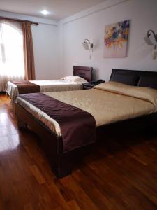 two beds in a room with a wooden floor at Hotel Plaza Real Suites & Apartments San Jose in San José