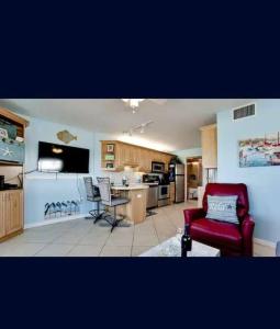 een woonkamer met een rode stoel en een keuken bij Beachfront condo in paradise in Bradenton Beach