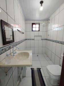 a white bathroom with a sink and a toilet at Refúgio na Praia in Ilhabela