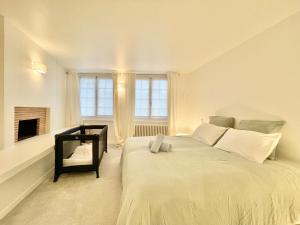 a white bedroom with a large bed and a fireplace at LA VILLA AU DUC - Standing - Jardin Clos - Plein Centre Ville ! in Quimper