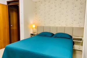- un lit bleu avec des oreillers bleus dans une chambre dans l'établissement Apto 3 quartos com piscina e pertinho da praia., à João Pessoa