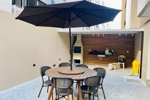 - une table en bois avec un parasol sur la terrasse dans l'établissement Apto 3 quartos com piscina e pertinho da praia., à João Pessoa