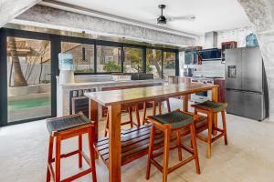 cocina grande con mesa de madera y taburetes en Villa Tankah 7 Cielo en Tulum