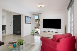 a living room with a red chair and a flat screen tv at La Marina in Puerto del Carmen