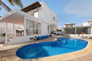 a villa with a swimming pool in front of a house at La Marina in Puerto del Carmen