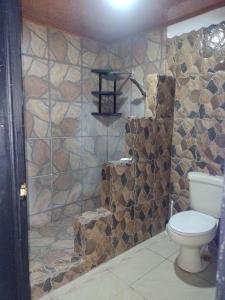 a bathroom with a toilet and a stone wall at Cabinas Pacifico in Puntarenas