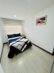 1 dormitorio con 1 cama y una pintura en la pared en Magnifico y confortable apartamento amoblado # 303, en Bogotá