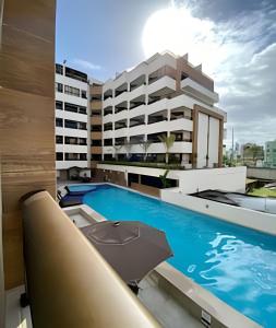 - un bâtiment avec une piscine et un parasol dans l'établissement Aptos super confortáveis no Gold Flat by Apartamentos Jampa, à João Pessoa