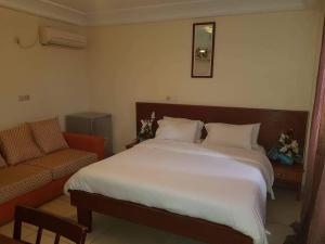 a bedroom with a large bed and a couch at Hannatel Rooms Liberté in Douala